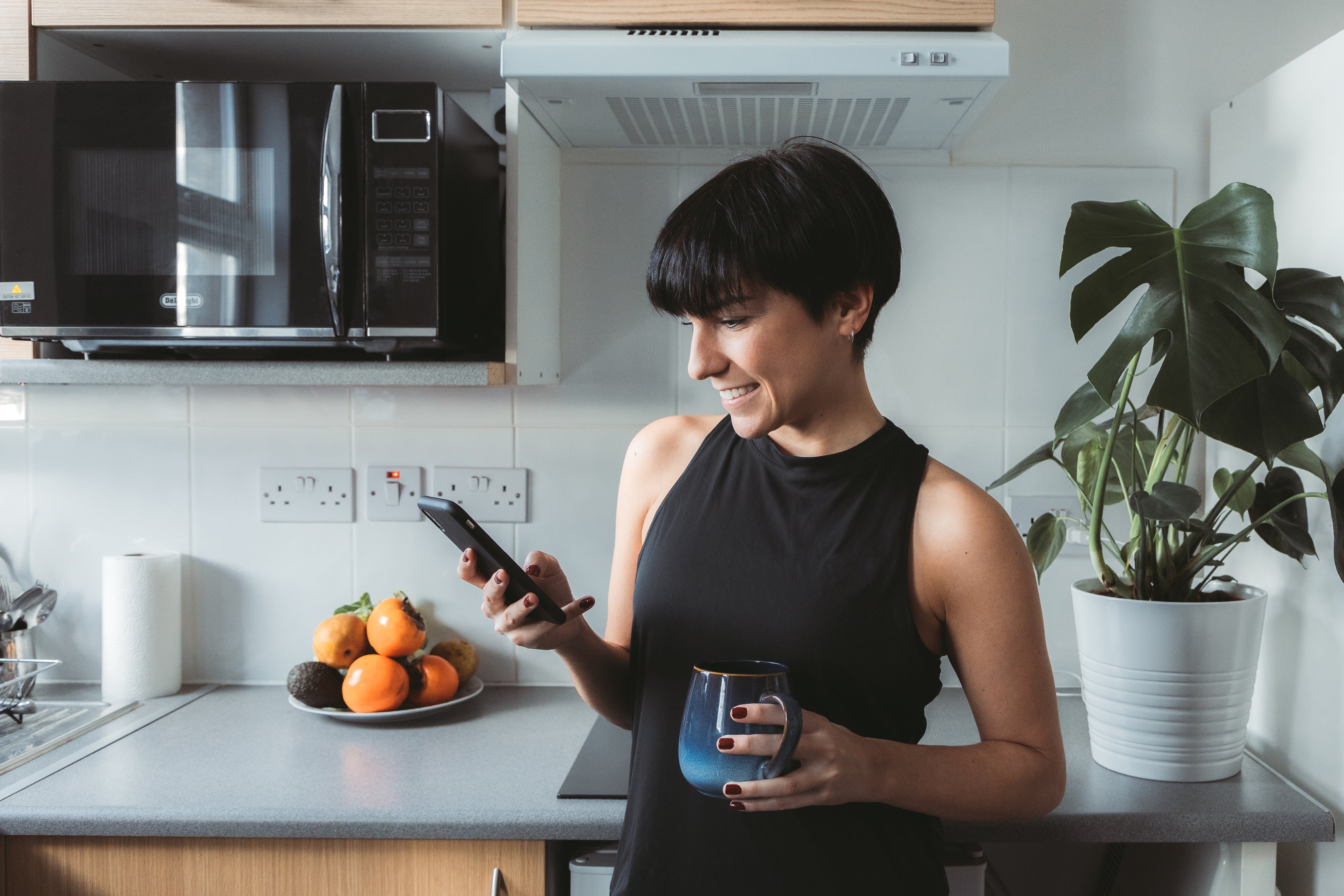 files/woman-stands-in-the-kitchen-and-smiles-while-using-cell-phone.jpg